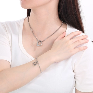 Polished silver beaded necklace and bracelet set with hollow heart pendants on model