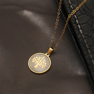Vue macro du pendentif arbre de vie doré avec fond blanc nacré sur cuir de couleur sombre