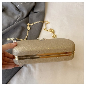 Detail of gold glitter clutch bag with crystal heart clasp and elegant chain strap