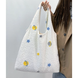 Detailed close-up of cartoon star embroidery on a plush white faux shearling tote bag