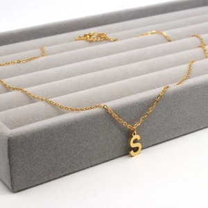 Macro view of gold stainless steel necklace featuring a polished capital letter S pendant