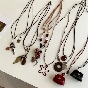 Bohemian sweater necklace featuring vintage leather bag pendants and feather charms