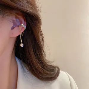 Detailed view of golden tassel ear cuff with sparkling zircon and heart pendant charms