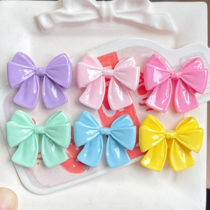Set of six colorful resin bow accessories in pastel tones on a decorative white tray