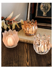 Three vintage tulip glass candle holders with lit tea lights in a warm rustic setting