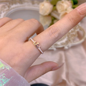 Detailed view of a rose gold crown ring with 'Queen' lettering and micro-pearl inlays