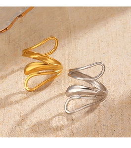 Close-up of gold and silver abstract wave rings on a textured stone surface
