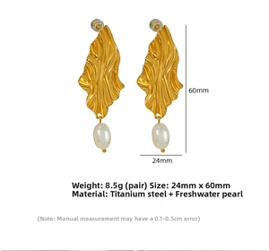 Macro detail of gold wavy drop earrings with white teardrop freshwater pearls