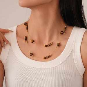 Close-up of double-layer gold chain necklace with tiger eye beads on model