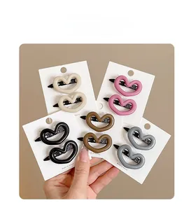Set of five heart-shaped hair clips in cream, pink, black, brown, and grey on cards