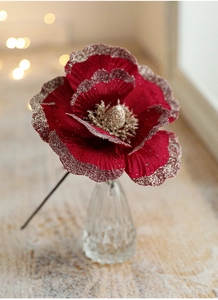 Close-up of velvet burgundy magnolia flower with gold glitter edges in glass vase