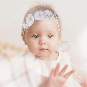 Detail of infant floral headband with delicate white fabric flowers for special occasions