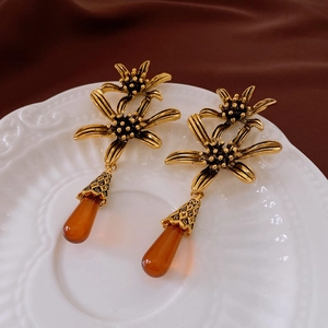 Detail of vintage gold flower earrings with amber teardrop pendants on a porcelain dish