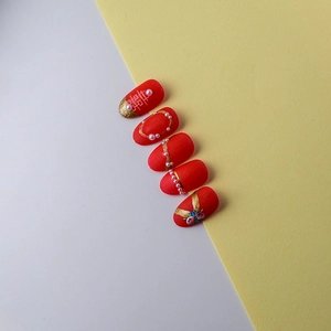 Detailed view of red bridal press-on nails with golden Double Happiness and pearls