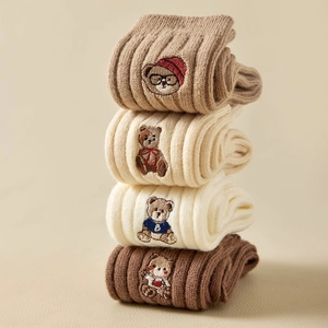 Detail of four pairs of thick winter socks with cute bear embroidery in autumn tones