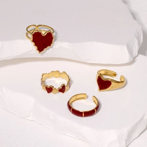 Detail of vintage gold stackable ring set with deep red enamel hearts on stone background