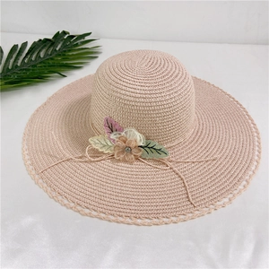 Detail of wide-brim straw hat featuring 3D floral accents and delicate lace edging