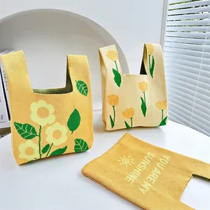 Knitted sunflower and tulip tote bags in yellow and beige on white display stands
