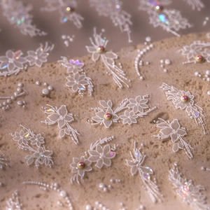 Elegant floral lace nail stickers with pearlescent beads on a natural stone surface