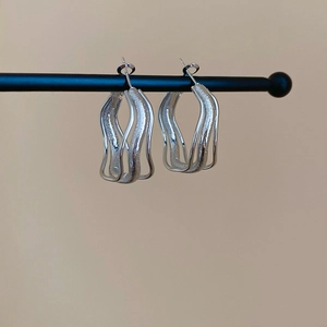 Detail of silver irregular double-layer geometric hoop earrings with matte and polished finish