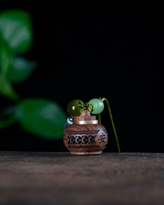 Detailed view of hand-carved sandalwood sachet pendant with green beads and safety character