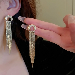 Macro shot of gold tassel earrings with C-shaped rhinestones and metallic chain fringe