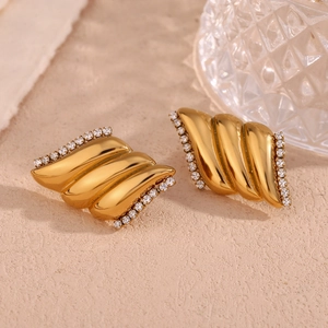 Dettaglio macro di orecchini a spirale placcati oro con zirconi bianchi stile lussuoso