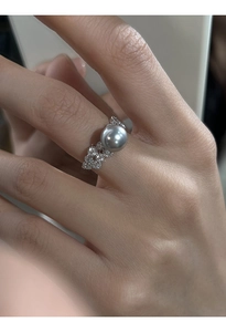 Detailed close-up of a silver ring featuring a grey pearl surrounded by clear zircons