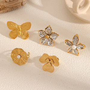 Detailed view of fashion stainless steel gold rings with butterfly and pearl flower motifs