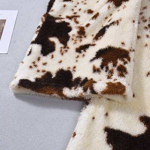 Gros plan du tissu polaire doux à motif vache montrant la texture luxueuse en peluche