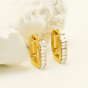 Boucles d'oreilles hexagonales dorées avec zircons clairs sur un support artistique