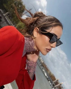 Detail of red lapel jacket paired with black rectangular sunglasses and purple lace collar