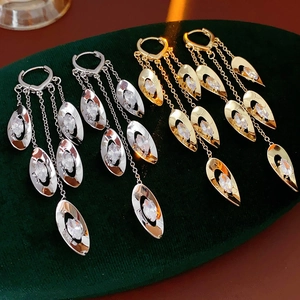 Détail de boucles d'oreilles à pompons dorés et argentés avec oxydes sur velours