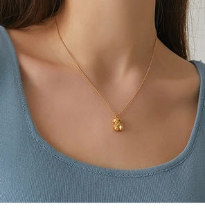 Detailed view of a golden geometric 3D bear pendant on a delicate beaded necklace chain