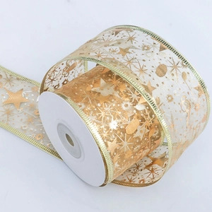 Detail of gold organza ribbon with festive star and musical note patterns on marble surface