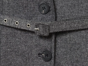 Détail de costume en tweed gris foncé avec boutons mats et ceinture à œillets métalliques