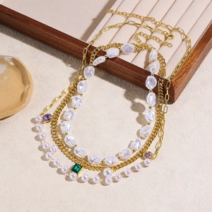 Close-up of layered baroque pearl necklace with colorful gemstones on a wooden tray