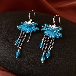 Detail of blue crystal tassel earrings with petal design on dark textured stand