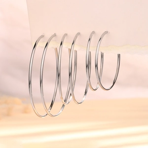 Detailed view of three pairs of silver hoop earrings in varying sizes on display
