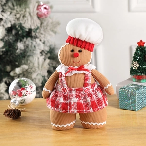 Detail of Christmas gingerbread girl plush doll with red plaid skirt and chef hat on wood