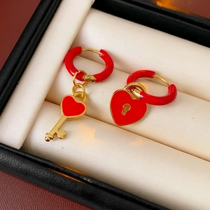 Detail of red enamel heart lock and key asymmetric earrings on a jewelry box cushion