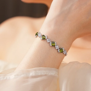 Detailed view of silver bracelet featuring olive green oval stones and clover link details
