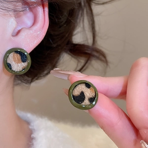Détail de la boucle d'oreille léopard avec bord en résine verte et texture douce