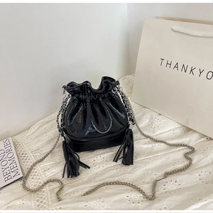 Close-up of black glossy bucket bag with croc-embossed texture and silver chain strap