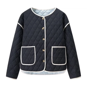 Detail view of diamond quilted navy jacket with white contrast trim and brown buttons
