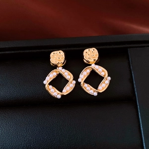 Close-up of 18K gold plated square earrings with hammered texture and pearl inlay