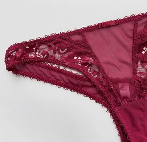 Detailaufnahme von weinrotem Spitzen-Mesh-Tanga mit floraler Textur und Schleifenakzent