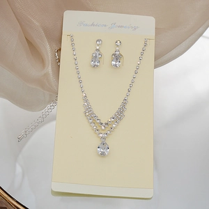 Macro detail of silver necklace and teardrop earrings set with sparkling rhinestones