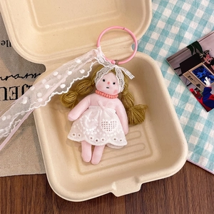 Detailed shot of floral plush doll keychain with lace dress in a cozy gift box setting