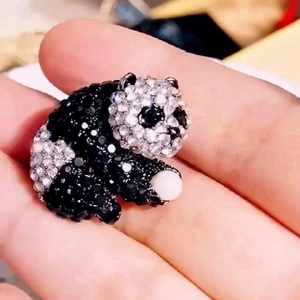 Macro shot of a cute panda brooch with black and white rhinestones holding a pearl